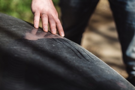 Car on a side of a dirt road, road trip in wilderness. the man has run finger over dirt. concept of travel and care of the car.の写真素材