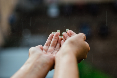 Hands catching clean falling rain ater close up. Environmental concept.