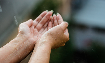 Hands catching clean falling rain drops close up. Environmental and healthcare concept.の写真素材
