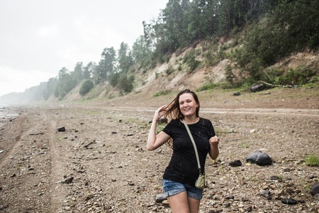 Wet woman enjoys a downpour rain shower in the forest