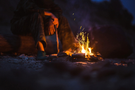 Person warms their feet next to a campfire at dusk camping in the woods.の写真素材