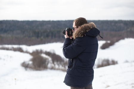 Photographer photographing winter panorama in hilly plain