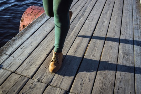 Female feet in brown boots and green pants on wood background. Walking fashion hiking concept.の写真素材
