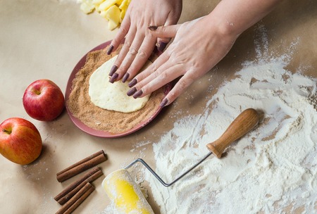 Preparation cookies with cinnamon, cottage cheese and apples on kraft paper. Female hands rolling dough in sugar. Homemade pastries. Christmas tradition baking, cakes and biscuits.の写真素材