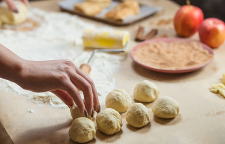 Preparation cookies with cinnamon, cottage cheese and apples on kraft paper. Female hands rolling dough in meals. Homemade pastries. Christmas tradition baking and cakes biscuits.の写真素材
