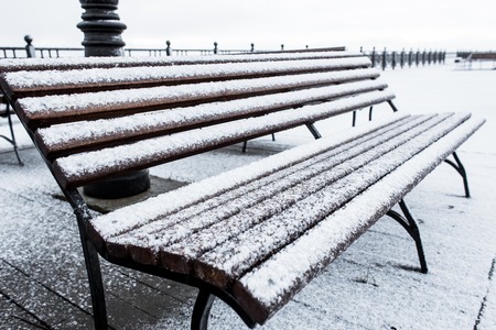 Frozen bench covered gritty rough hoarfrost on a cloudly winter day.の写真素材