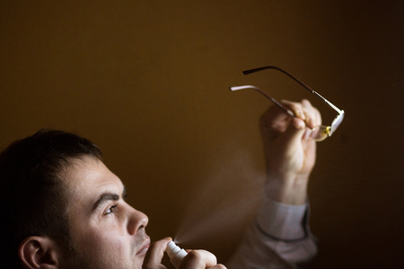 Man cleaning a spray pair of reading glasses spectaclesの写真素材