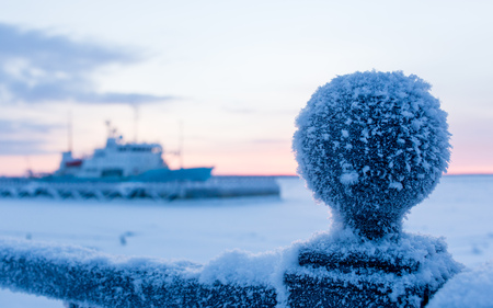 Frosty morning, an iron chain on the embankment covered with a thick layer of frost, and sea frozen ship on bokehの写真素材