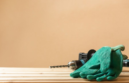 Green working gloves with green drill on lining wooden table with copy space.の写真素材