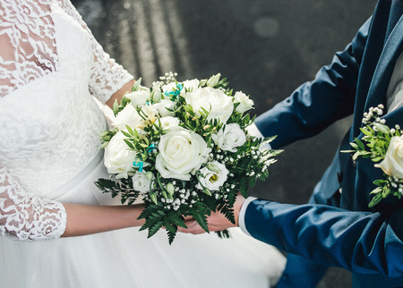 Detail of brides white roses bouquet and hands holding.の写真素材