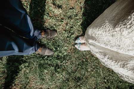 Top view of fashionable grooms and brides legs in elegant footwear on grass. Wedding fashion and relationship concept.の写真素材