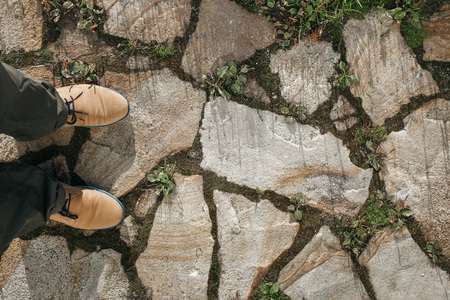 Male feet standing on the paved street in black shoes. First person POV. Top view. Vertical picture.の写真素材