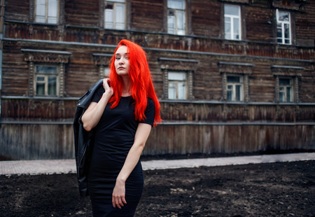 Portrait of beautiful redhead girl on wooden wall of village house Unformal woman with vibrant colorful hairstyle.の写真素材