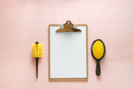Flat lay of hair comb crest brushes with handle for all types, pocket mirror and folder tablet, isolated on pink copy space background. Minimalistic feminine flat lay for bloggers, designers, sites.の写真素材