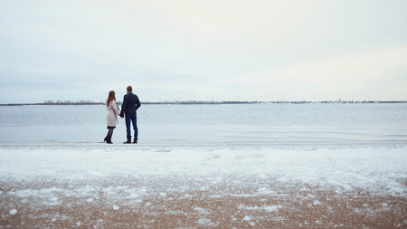 Romantic couple enjoying nature together on the background of the coastline. Happy winter moments,...