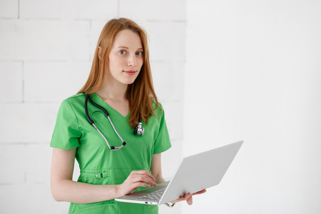 Portrait of beautiful friendly doctor using laptop computerの写真素材