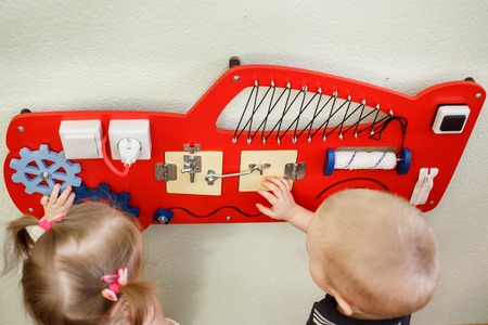 Cute toddlers playing with busy board at kindergartenの写真素材