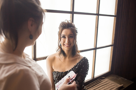 Pretty woman make up artist applying makeup to beautiful latina girlの写真素材