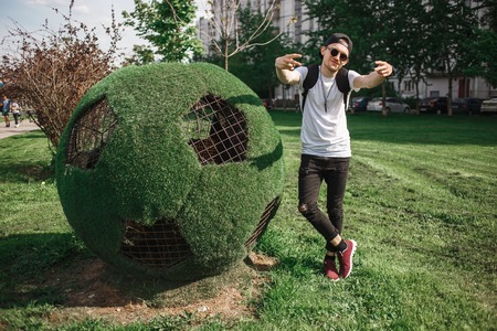 Stylish handsome man tourist posing near soccer ball symbol of grass.の写真素材