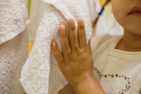 Girl in a bathroom wipes the washed up hands a towelの写真素材