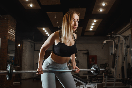 Young woman lifting barbell with light weights at gym. Fitness female doing crossfit workoutの写真素材