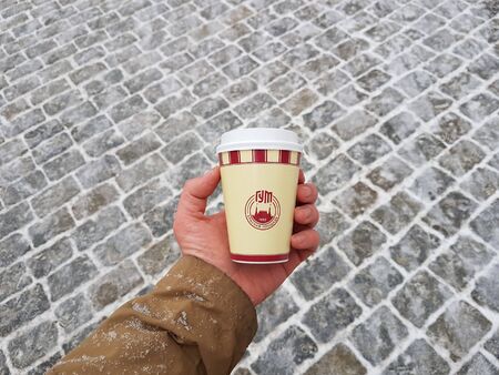 Moscow, Russia, December 9, 2018: Hot drink in a disposable cup in hand on Christmas Eve on the...