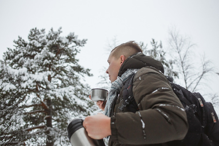 Stylish  with a  of hot tea in a snowy conifer forest