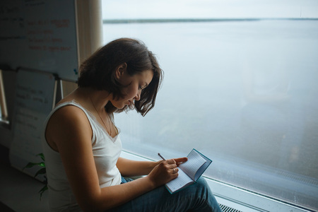 Pretty woman writing notes in the notebook in office.の写真素材
