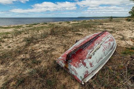 Old abandoned battered fishing boat on the sea coastの写真素材