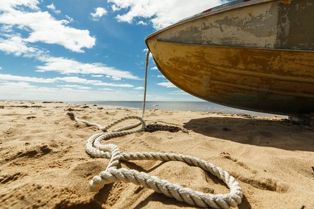 Old fishing boat with rope on a sandy beachの写真素材