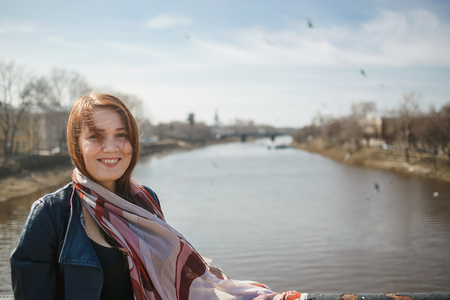Pretty girl in a scarf and leather jacket in spring city. Concept of spring, freedom, travel and windy weatherの写真素材