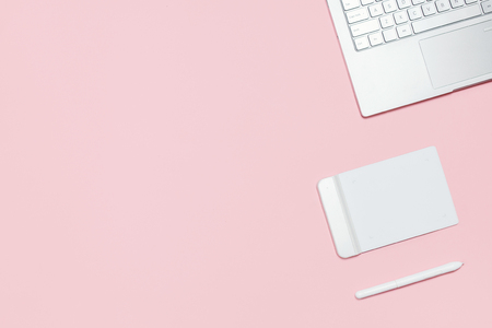 Modern workspace of photographer, illustrator or designer. Pink table with laptop, graphic tablet with pen. Top view. Flat lay template with copy spaceの写真素材