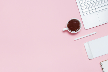 Modern workspace of photographer, illustrator or designer. Pink table with laptop, graphic tablet with pen and cup of coffee. Top view. Flat lay template with copy spaceの写真素材
