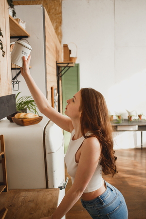 Young girl in the kitchen holding can of teaの写真素材
