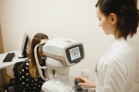 Attractive female doctor ophthalmologist is checking the eye vision of patient in modern clinicの写真素材