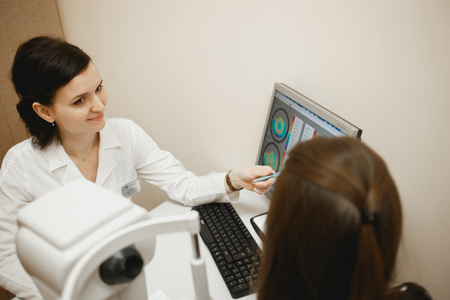 Attractive female doctor ophthalmologist is checking the eye vision of patient in modern clinicの写真素材