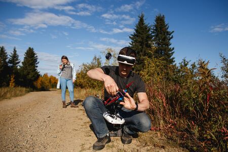 Narian-Mar, Russia - September 11, 2019: Man preparing race drone for the flight on the forest road. Close up for the process of Custom drone setup and drone assembly, modern technologies conceptのeditorial素材