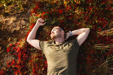 Season, happiness and people concept - smiling young man lying on ground or grass, moss and fallen...