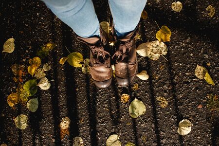 Boots on fall leaves Outdoor with Autumn. Beautiful Female feet in brown leather boots and laces fall autumn leaves on for season, footwear, people and nature concept. Sunny weather. Top view copy spaceの写真素材