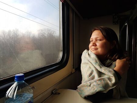 Young woman traveling looking out the window while sitting in the train. Russian reserved seat