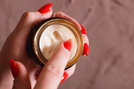 Female hands with red nails applied hand cream. Texture of cream closeup view