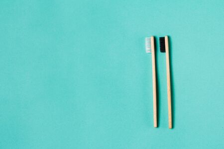 Two wooden bamboo eco friendly toothbrushes on aquamarine background. Dental care and zero waste...