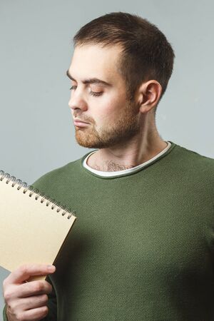 A young white man holds a notebook. Concept training, internship Vertical image