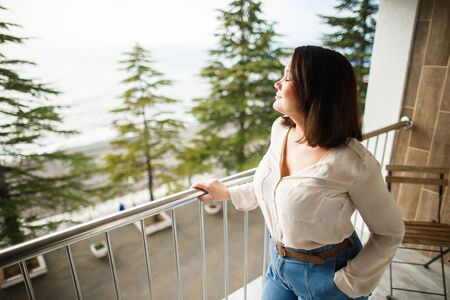 Beautiful girl enjoys the sound of the surf on the balcony of the room