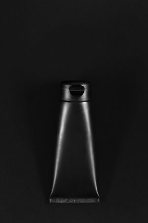 Black cream tube on black table. Royal product. Empty place for logo on tube. Directly above lowkey flat layの写真素材
