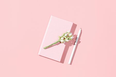 Pink notebook, blossom flower branch on pink background. Spring feminine mockup. Flat lay, top view, copy spaceの写真素材