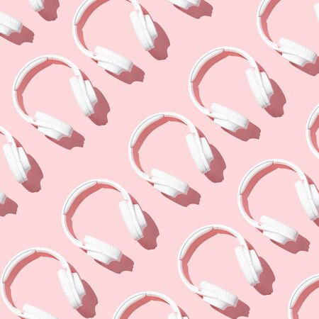 Pattern white headphones on modern pale pink table top view flat lay. Free space for creative design text and contentの写真素材
