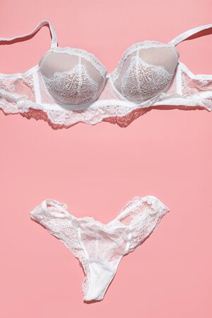 Sexy white lace bra and panties on pink background. Stylish lingerie flat lay. Underwear fashion conceptの写真素材