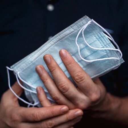 Medical masks made of cotton in mens hands. The concept of protection against respiratory diseases and epidemicsの写真素材
