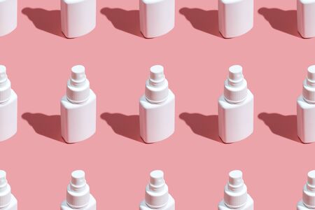 Regular Pattern of spray sanitizer tubes on the pink table flat lay. Fabric medical production,...
